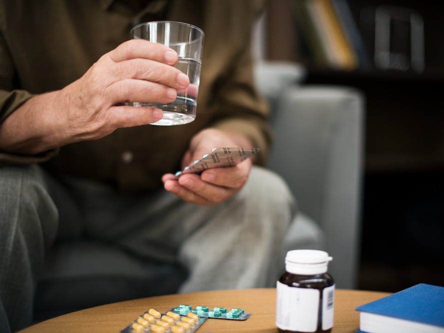 Man holding medication and a glass of water